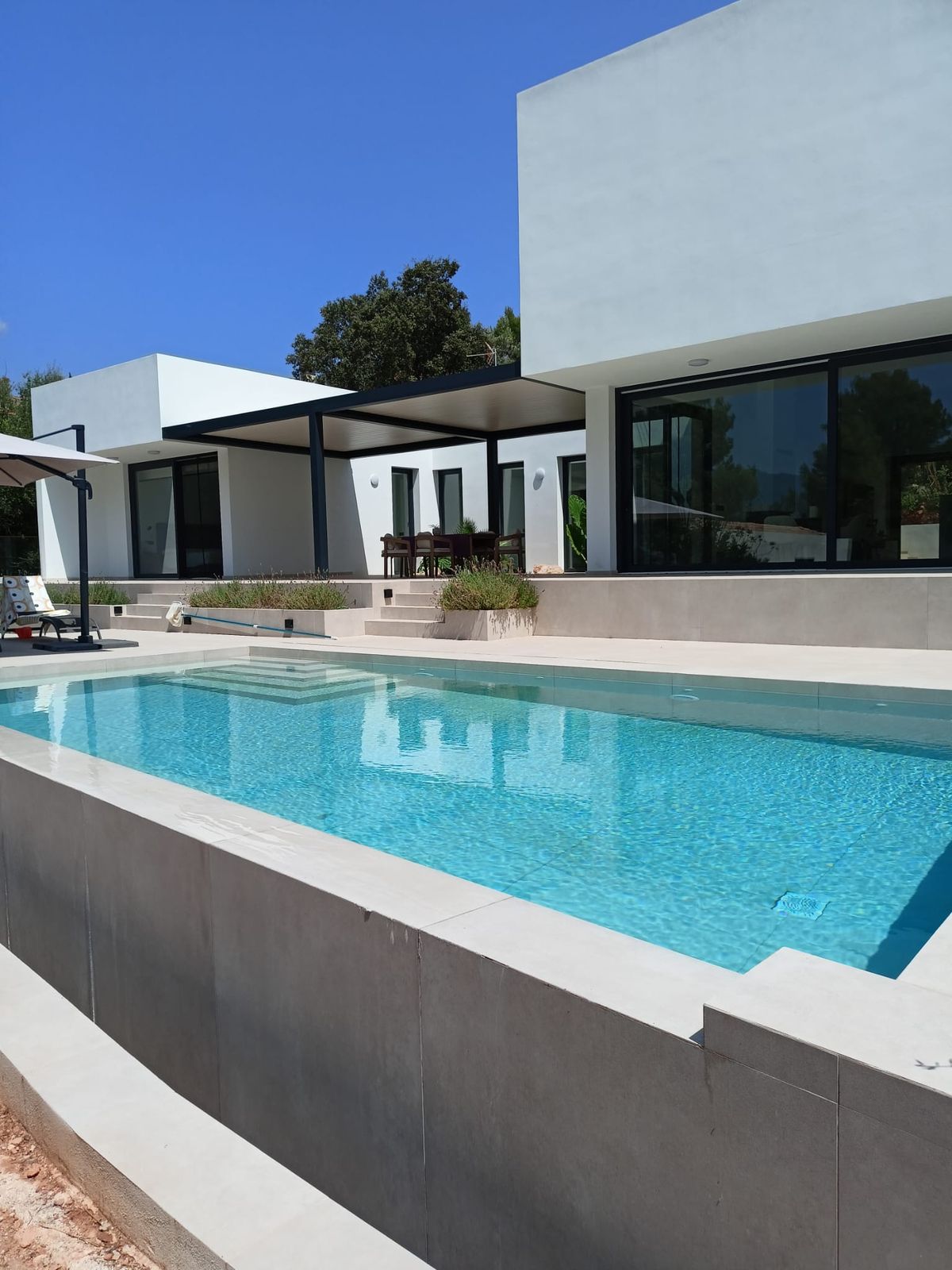 Villa renovated in Mallorca by Las Marquesinas: white façade, black aluminium windows, pergola and swimming pool with porcelain coping