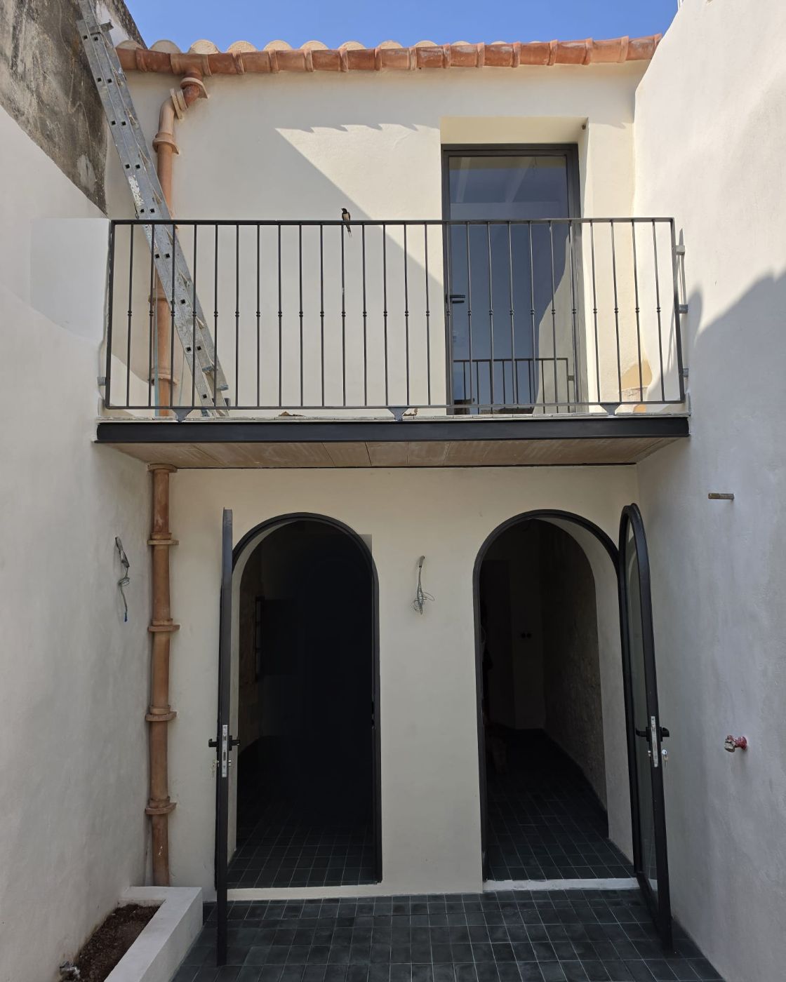 Courtyard of a renovated village house in Sineu: rendered façade, clay tile roof and a new balcony railing