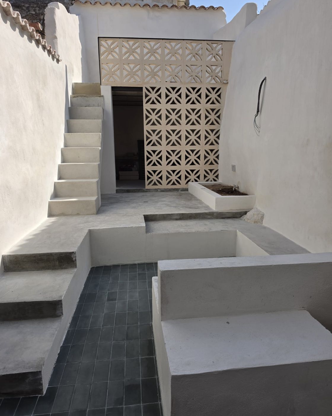 Concrete staircase and ceramic lattice screen in the courtyard of a renovated house in Sineu