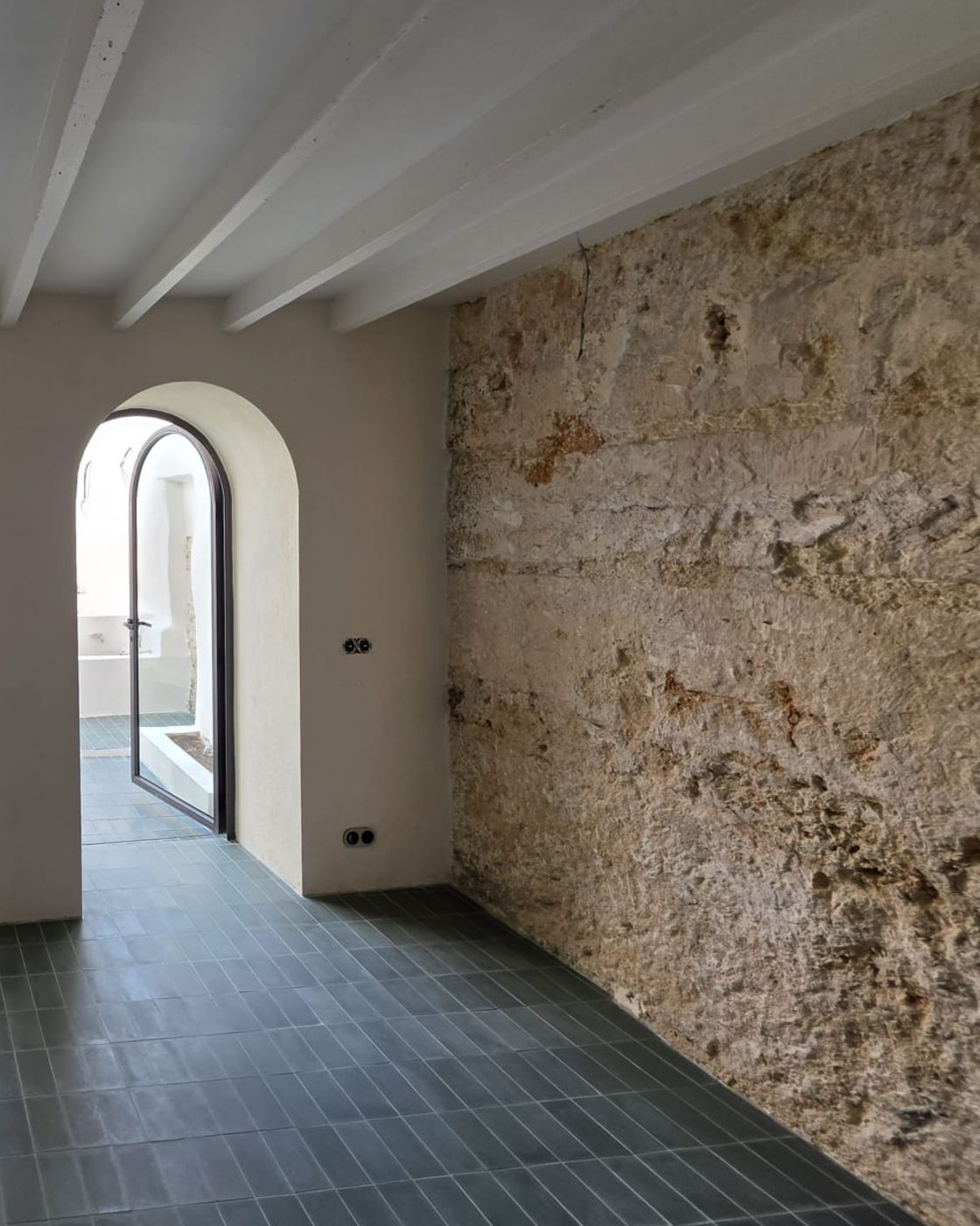 Restored marés sandstone wall and painted beams inside a renovated house in Sineu